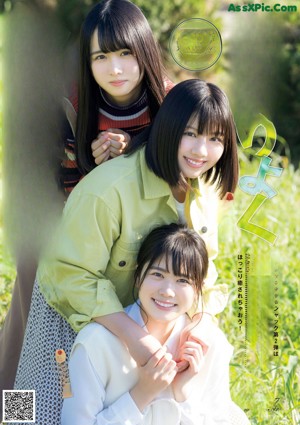 A group of young women standing next to each other near a fence.