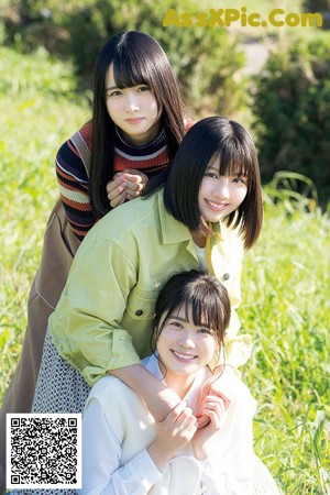 A group of young women sitting on top of a lush green field.