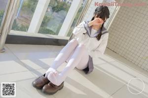 A woman in a school uniform sitting on a chair.
