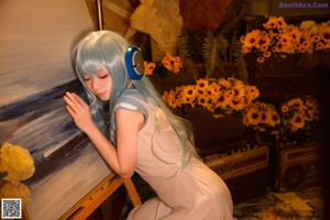 A woman in a white dress sitting on a chair with headphones on.