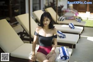 A woman in a black dress standing next to a pool.