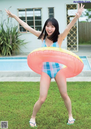 A woman in a blue bikini posing by a swimming pool.