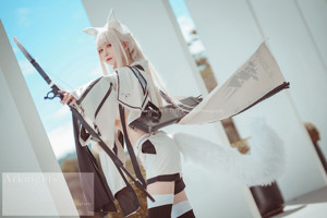 A woman dressed in a white outfit holding a bow and arrow.