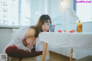 A woman in a red and white polka dot bikini sitting on a bed.