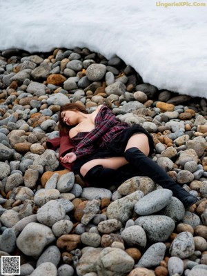A woman laying in the snow in a black coat.