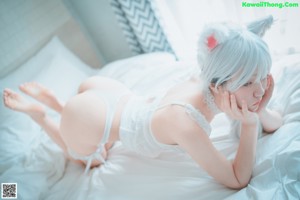 A woman in a white dress sitting on a bed.
