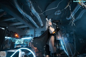 A woman in a black dress holding a gun in a room.