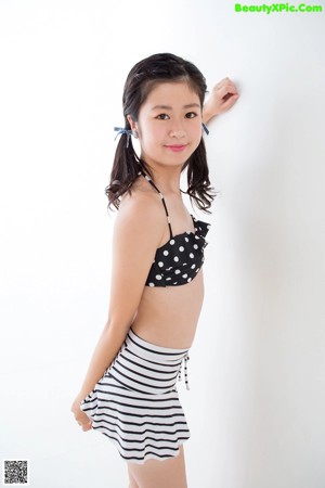 A woman in a black and white polka dot top and striped skirt.
