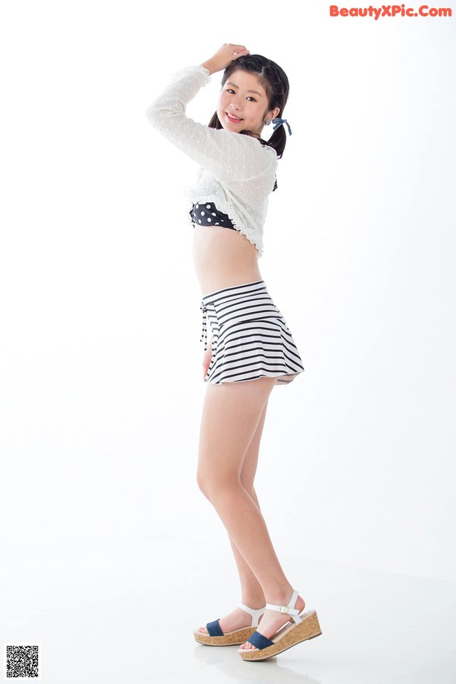 A woman in a white top and black and white striped shorts.