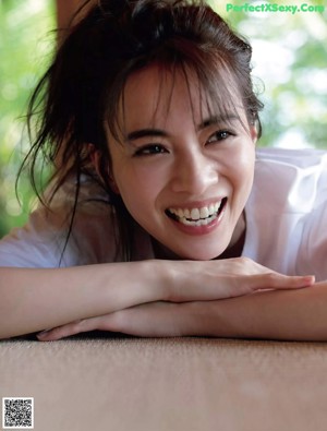 A woman crouching down on the grass in a park.