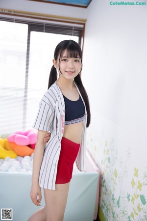 A woman in red shorts and a black top posing for a picture.
