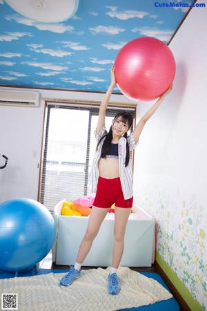 A young woman is posing on a red ball.