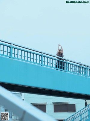 A woman in a white bra looking out a window.