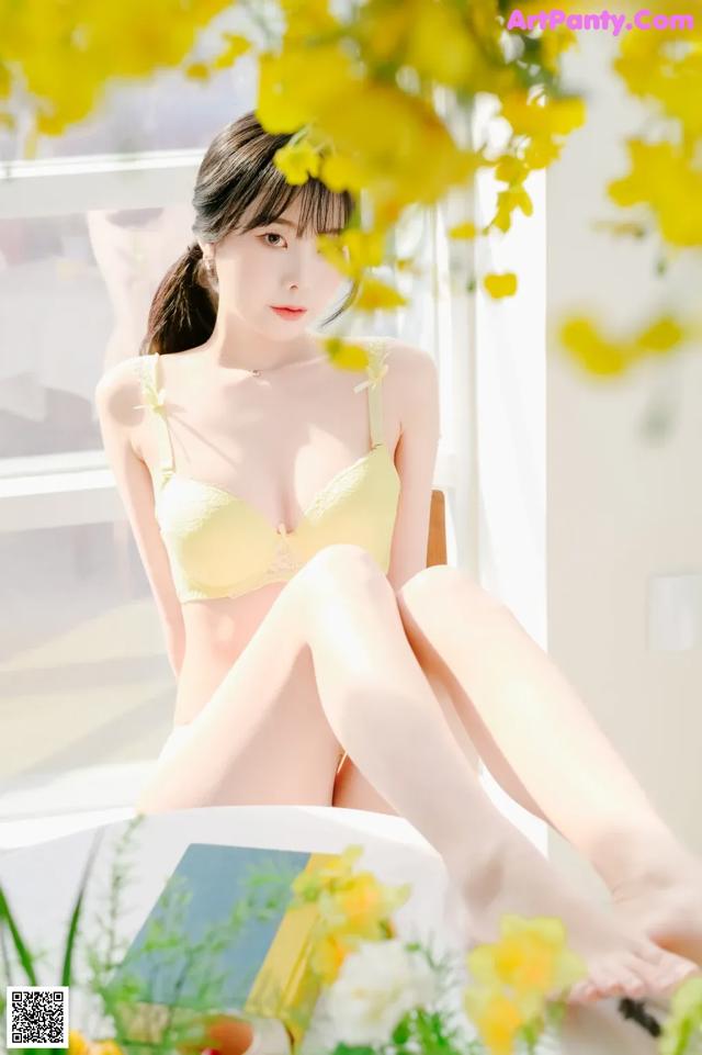 A woman in a yellow bra sitting on a window sill.
