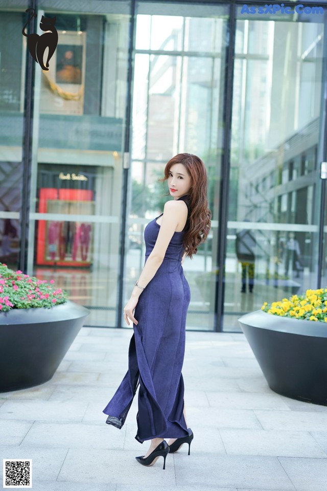 A woman in a blue dress standing in front of a building.