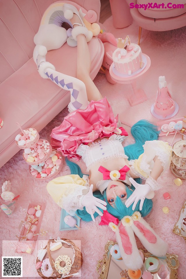 A woman laying on a pink couch surrounded by sweets.