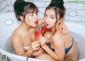 A couple of women standing next to each other on a bed.