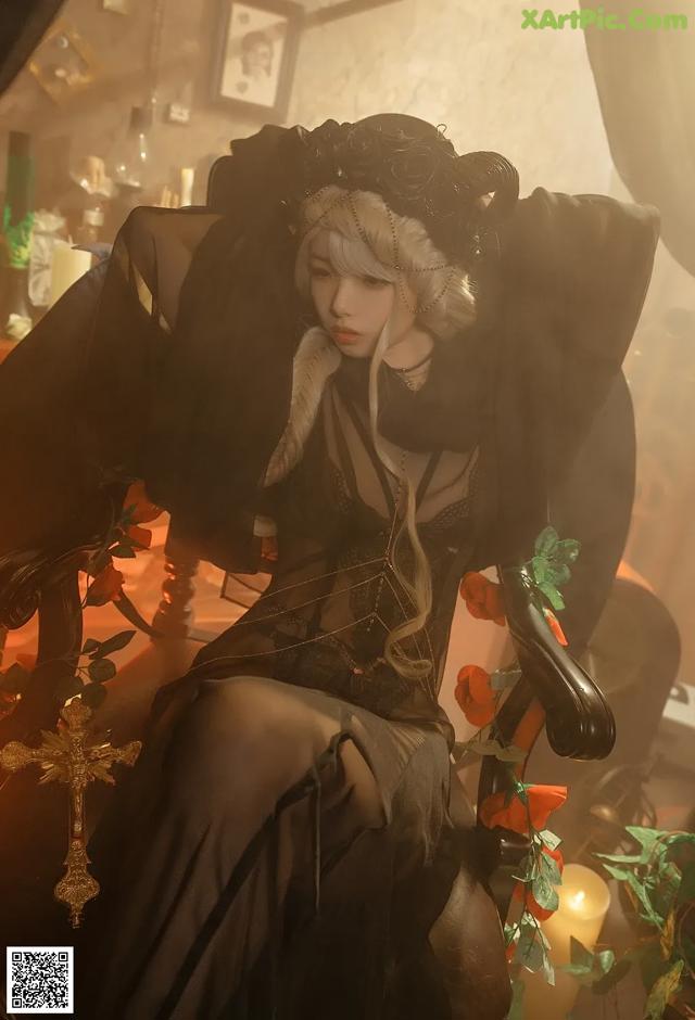 A woman in a black dress sitting on a chair.