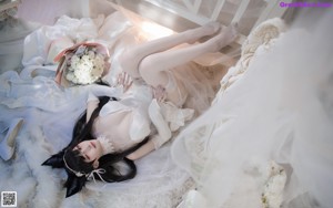 A woman in a white dress laying on a fluffy white rug.