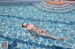 A woman in a blue bikini is swimming in a pool.
