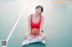 A woman sitting on a bench with a basketball.